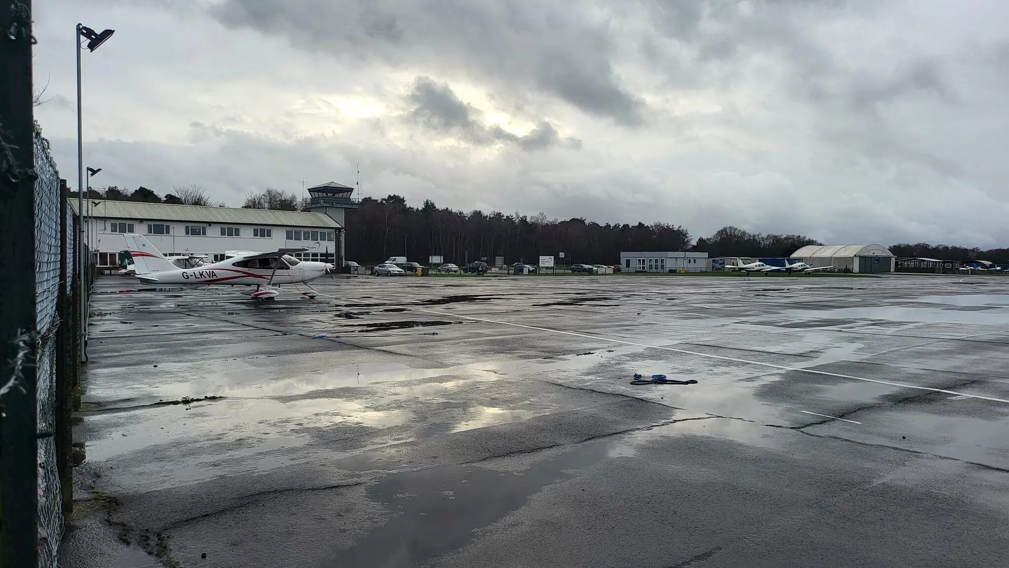 Blackbushe Airport control tower, terminal building and parked light aircraft photographed in January 2022