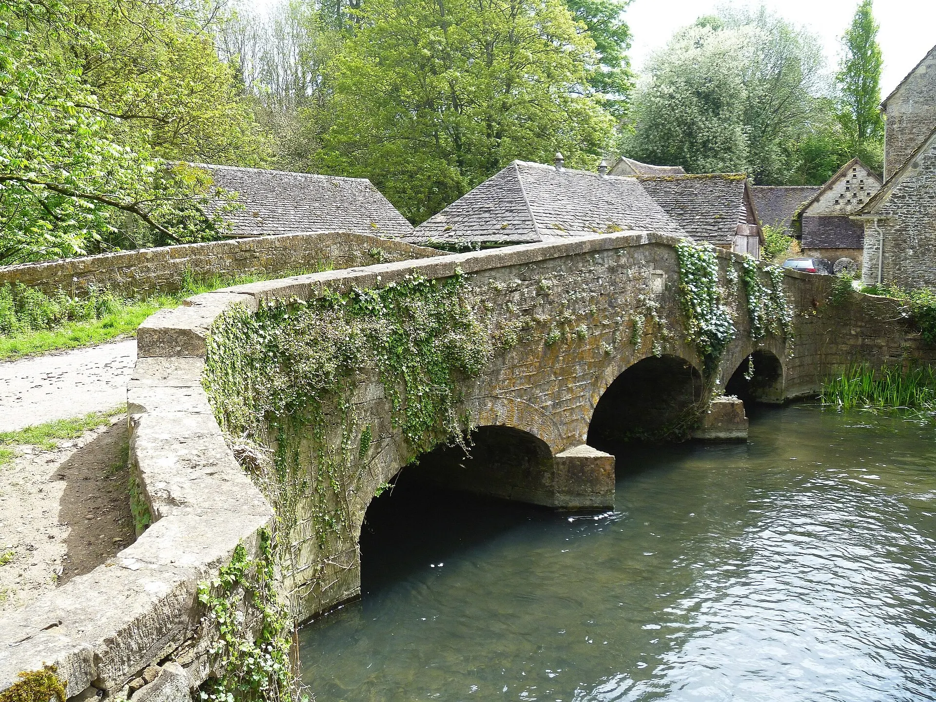 Stone bridge and village buildings beside the river in Bibury