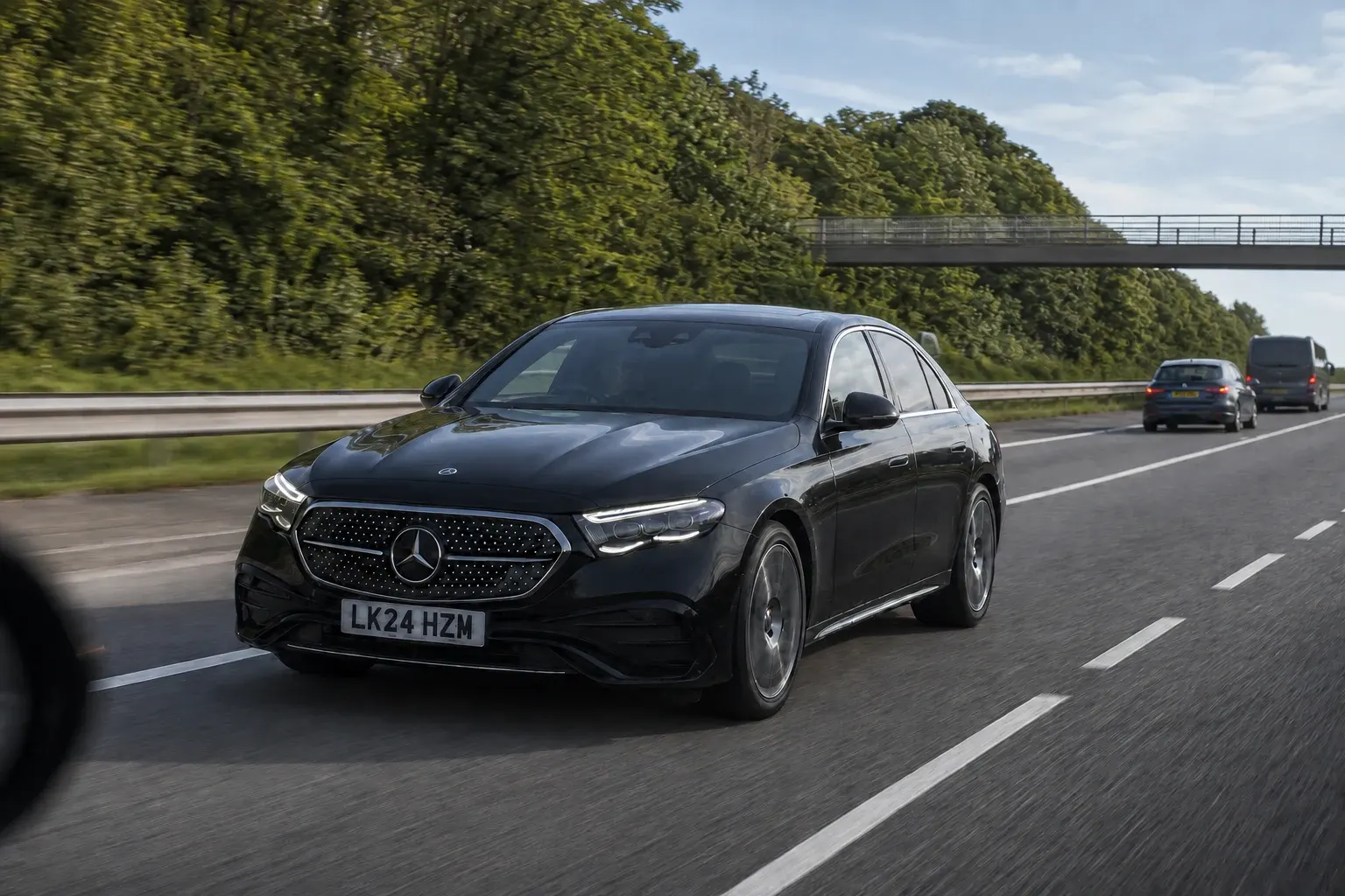 Black chauffeur saloon travelling on a tree-lined motorway