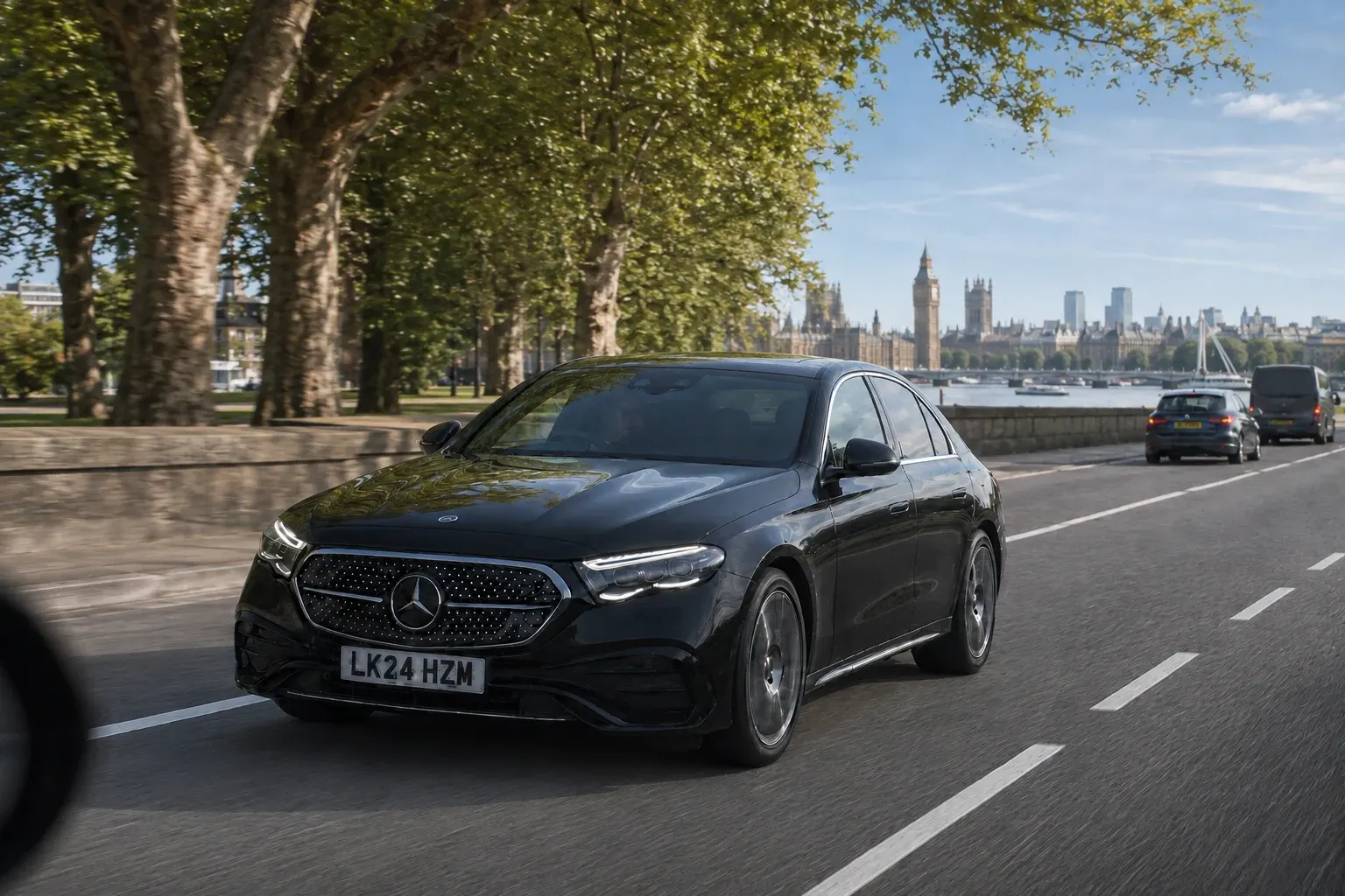 A black chauffeur saloon travelling beside the Thames on a clear city road